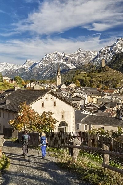 Hikers admire Ardez village surrounded by woods and snowy peaks Lower Engadine Canton
