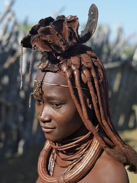 A Himba woman in traditional attire. Her body gleams from a mixture of red ochre