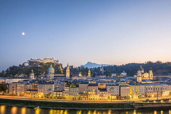 Historical old town of Salzburg reflected in Salzach river at dusk with Hohensalzburg