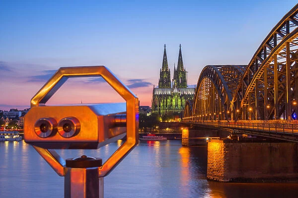Hohenzoller Bridge over River Rhine and Cologne Cathedral with binoculars at dusk
