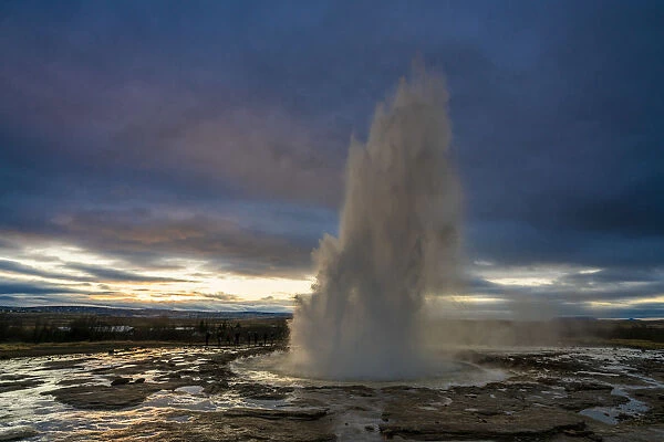Hot spring splashing at Strokkur against cloudy sky during sunset, Geysir, South Iceland