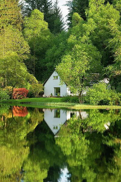 House amongst trees with reflections, Loch Ard, Aberfoyle, Stirling, Perthshire, Scotland, UK