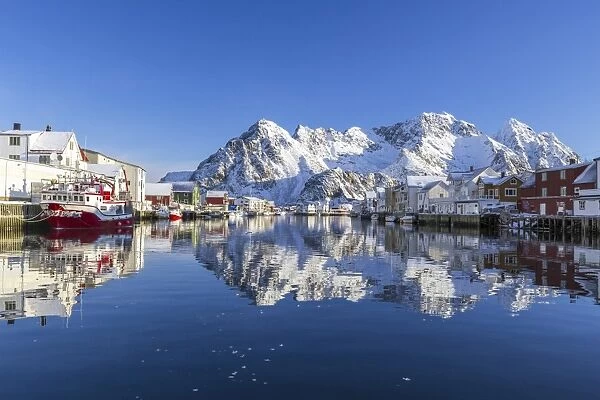 Houses and mountains reflected in the waters of Henningsvaer fjord. Lofoten Islands