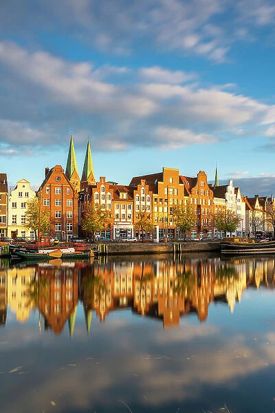 Houses on riverfront of Trave river with towers of St. Marienkirche church in background at sunset, Lubeck, UNESCO, Schleswig-Holstein, Germany