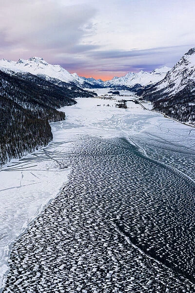 Ice and snow covering Lake Silvaplana during the winter sunrise, aerial view, Maloja