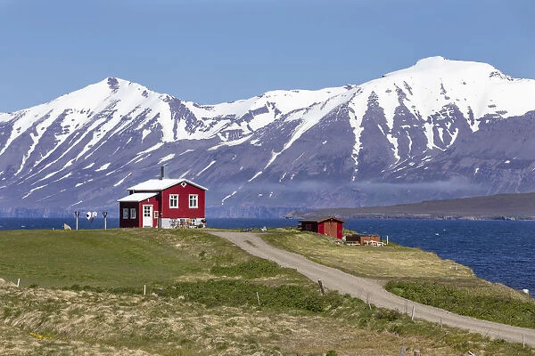 Iceland, Akureyri, a pretty red house on the Eyjafjorður with snow capped mountains in the distance