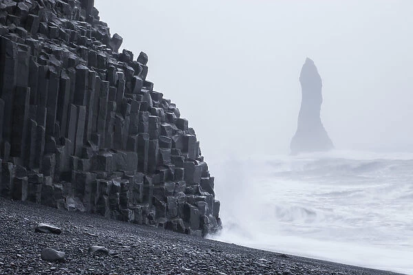 Iceland, Basalt columns on the Viks beach and cliffs wrapped in mist
