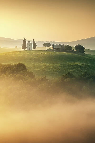 The iconic Chapel of Madonna di Vitaleta appearing through the thick layer of fog on a sunny spring morning. Val d'Orcia, Tuscany, Italy