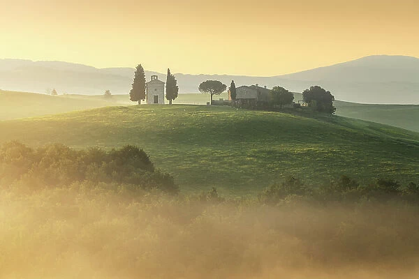 The iconic Chapel of Madonna di Vitaleta appearing through the thick layer. Val d'Orcia, Tuscany, Italy