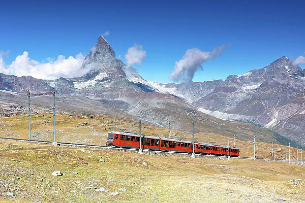 the iconic red train over the Gornegrat railway, with the Matterhorn mountain in background, Zermatt, Canton of Valais, Switzerland