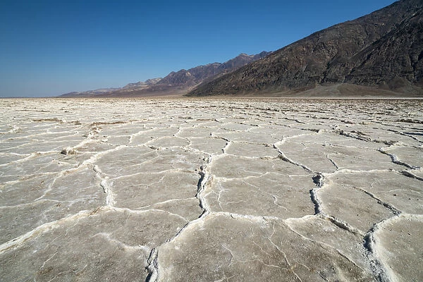 Idyllic view of salt pans by rocky mountains on sunny day, Badwater Basin