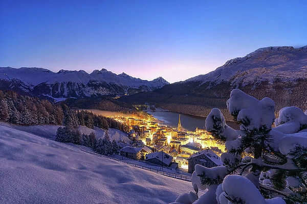 Illuminated village of Saint Moritz covered with snow at dusk, Graubunden canton, Engadin, Switzerland