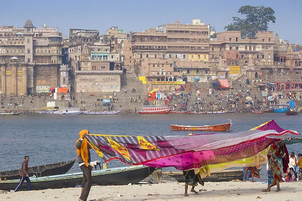 India, Uttar Pradesh, Varanasi, Hanging up washing on banks of Ganges river opposite