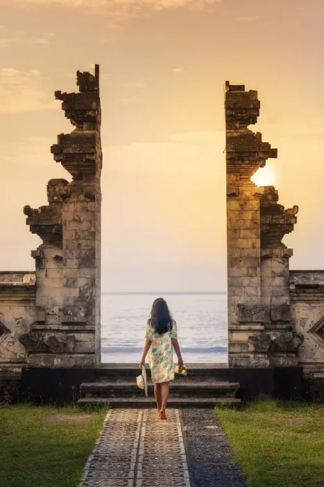 Framed Print : Indonesia, Bali, Candidasa. A young woman walking through the doorway of a traditional Framed Print : Indonesia, Bali, Candidasa. A young woman walking through the doorway of a traditional