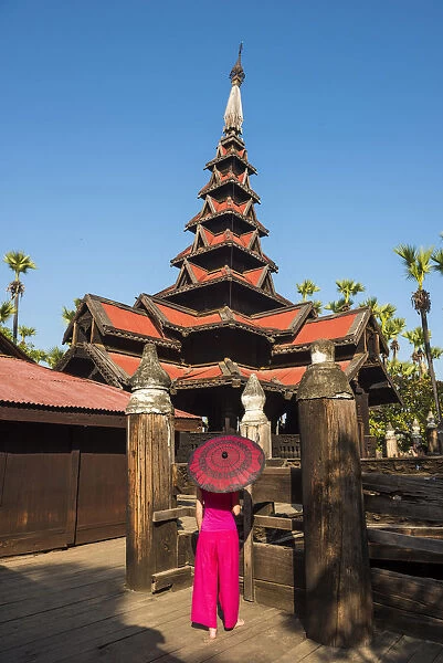 Inwa, Mandalay region, Myanmar (Burma). A woman with red dress and umbrella in the