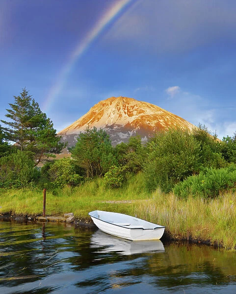 Ireland, Co. Donegal, Boat in lake infront of Mount Errigal with rainbow
