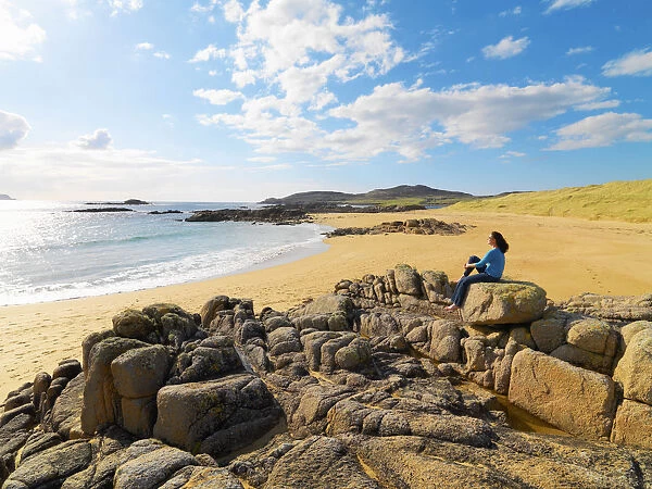 Ireland, Co. Donegal, Cruit island, Woman sitting on rocks (MR)