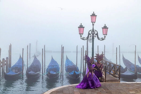 Italy, Veneto, Venice, a couple pose in costume during the Venice Carnival on a foggy day