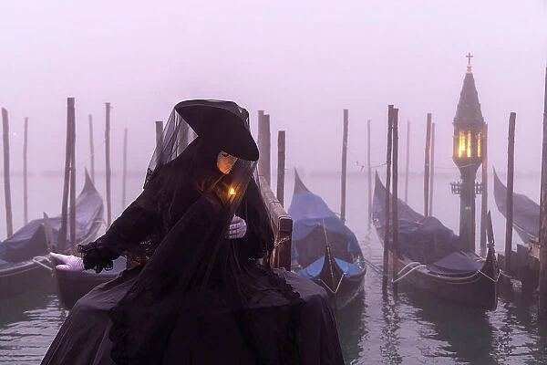 Italy, Veneto, Venice, a model poses in costume during the Venice Carnival on a foggy day
