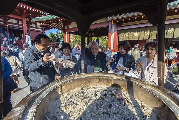 Japanese worshippers rubbing with the so said healthy smoke coming from the large
