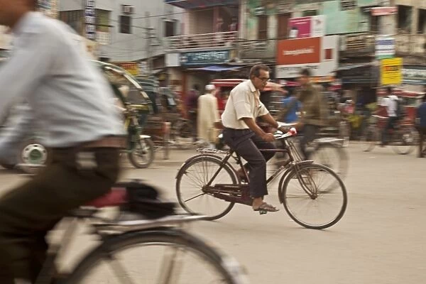 Jessore, Bangladesh. A man cycles to work through the centre of town