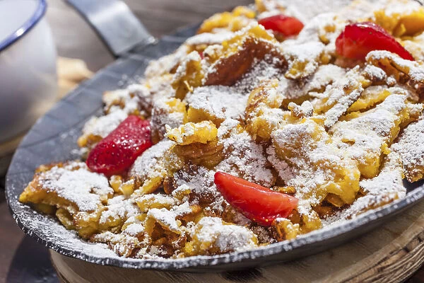 Kaiserschmarrn with strawberries in an iron pan on a mountain hut in Reintal, South Tyrol, Italy