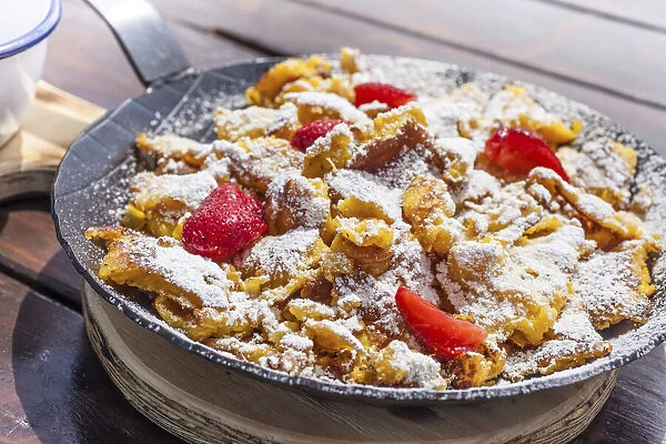Kaiserschmarrn with strawberries in an iron pan on a mountain hut in Reintal, South Tyrol, Italy