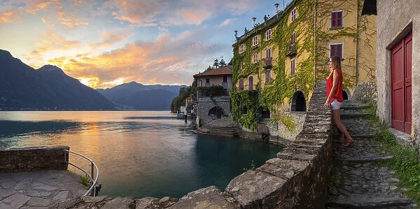 A lady observes sunset at Nesso, Como lake, Como, Lombardy, Italy (MR)