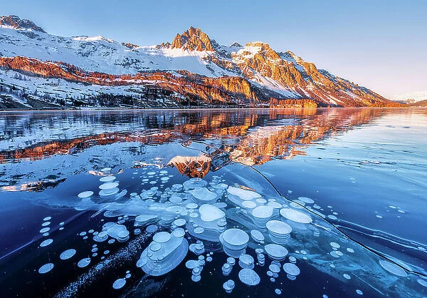 Lake Sils covered of ice bubbles at sunset, canton of Graubunden, Engadine, Switzerland