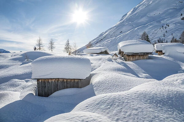 landscape of snow-covered mountain huts in the locality Ciamp de Lobia, Fedaia pass