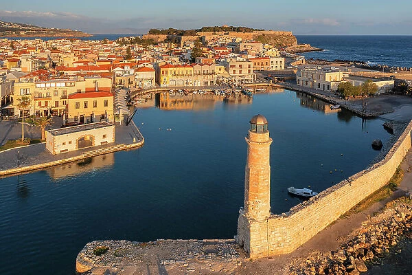 Lighthouse at the Venetian harbor with a view of Venetian Fortezza, Rethymno, Crete, Greece
