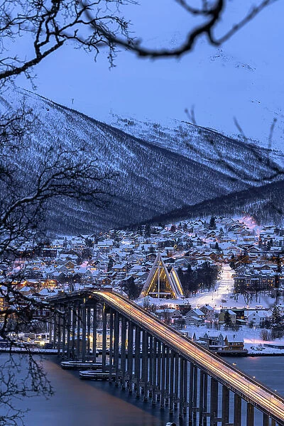 Lights of car trails on Bruvegen Bridge with the snowy Arctic Cathedral on background, Tromso, Norway