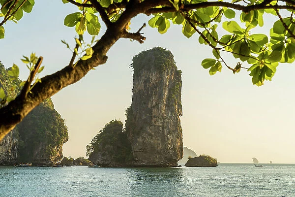 Limestone Karst tower framed by trees on Pai Plong Beach, Ao Nang, Krabi, Thailand