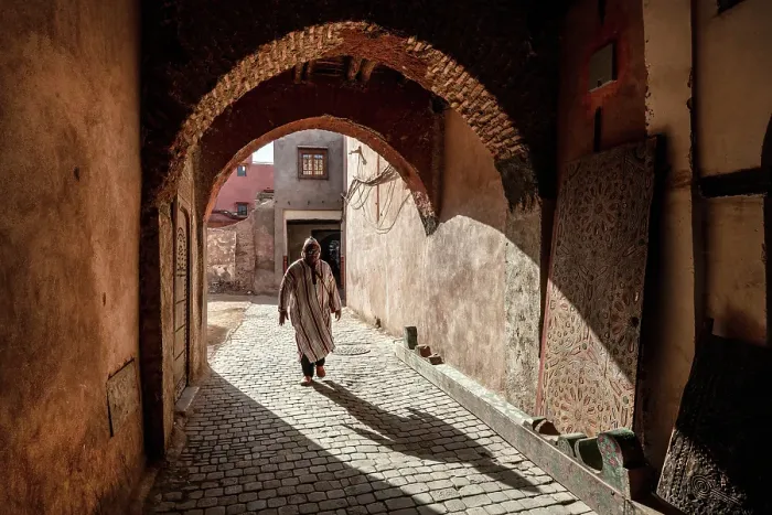Framed Print : Local man in djellaba, walking through an archway on cobbled street, Medina, Marrakech, Morocco