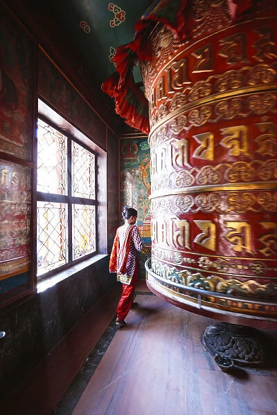Local woman circling around a prayer wheel, Boudhanath stupa, Kathmandu, Nepal (MODEL