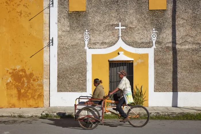 Framed Print : Locals on a tricycle passing by the front facade of a colonial house in Izamal, Yucatan, Mexico Framed Print : Locals on a tricycle passing by the front facade of a colonial house in Izamal, Yucatan, Mexico