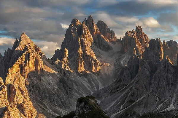 A lone person standing against the rugged Cadini di Misurina in the background at sunset. Dolomites, Italy