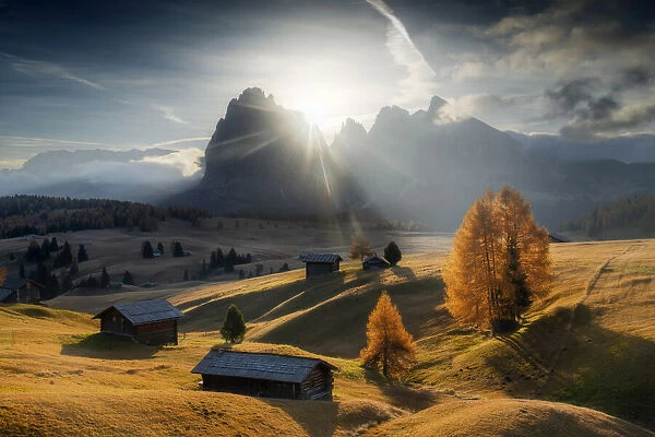 The lonely cabins of the Alpe di Siusi (Seiser Alm) during a sunny autumn morning, with the mountains in the background. Dolomites, Italy