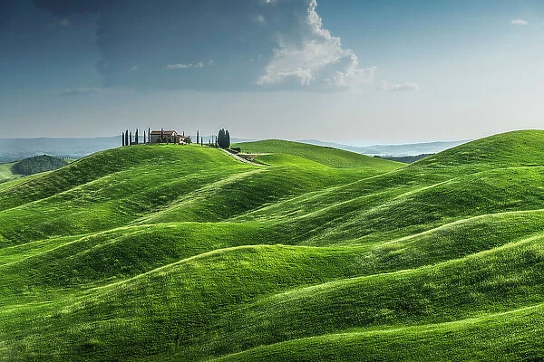 A lonely countryhouse and some rolling hills in the Crete Senesi. Tuscany, Italy