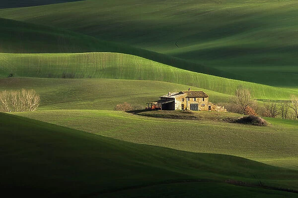A lonely farmhouse is taking the late afternoon light during a winter day. Val d'Orcia, Tuscany, Italy