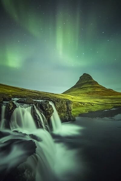Long exposure landscape with waterfalls and aurora borealis above Kirkjufell Mountain