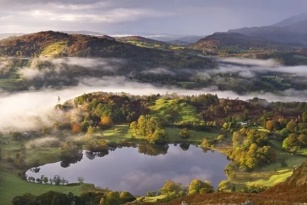 Loughrigg Tarn surrounded by misty autumnal countryside, Lake District, Cumbria, England