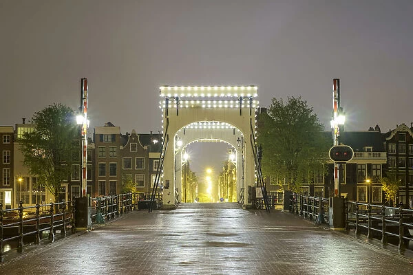 Magere Brug illuminated at night on foggy evening, Amsterdam, North Holland, Netherlands