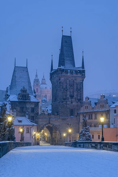 Mala Strana Bridge Tower at snow-covered Charles Bridge at twilight in winter, Prague