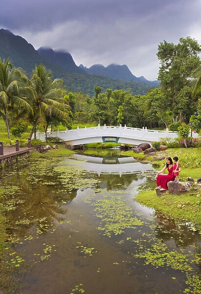 Malaysia, Langkawi, Oriental Gardens, Woman and girl sitting by lake MR