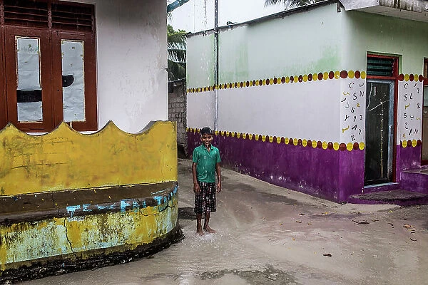 Maldives, Ari Atoll, Himandhoo, A young boy under the rain