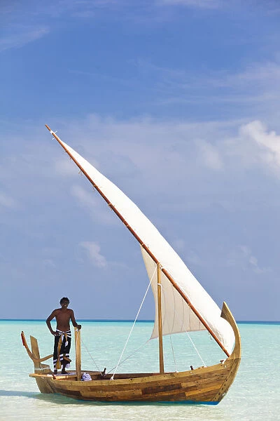 Maldives, Rasdhoo Atoll, Kuramathi Island. A Maldivian man sails a traditional Dhoni. MR