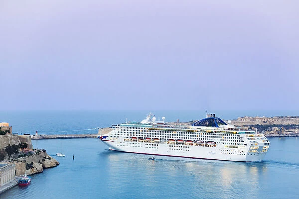 Malta, South Eastern Region, Valletta. A cruise ship leaves Grand Harbour at dusk