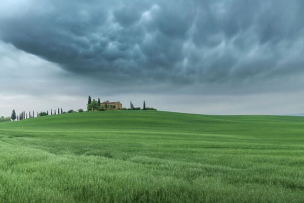 Mammatus clouds formations appearing over a countryhouse in the rolling hills of Val d'Orcia, Tuscany, Italy