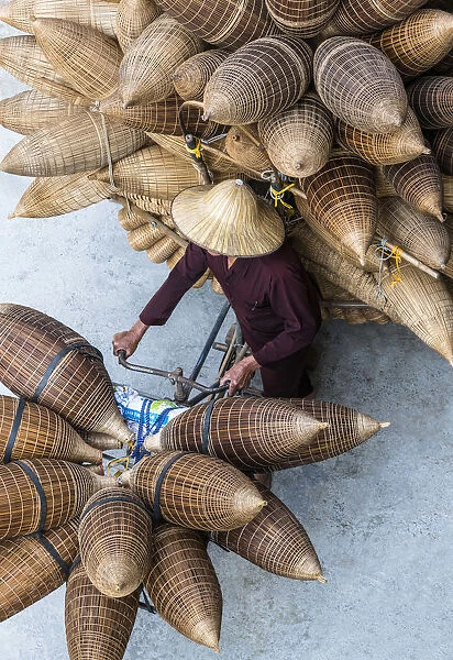 A man on the bicycle loaded with the conical bamboo fish traps, near Hanoi, Vietnam